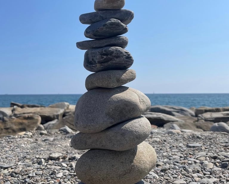 des galets empilés pour former un cairn avec en fond la mer et le ciel bleu