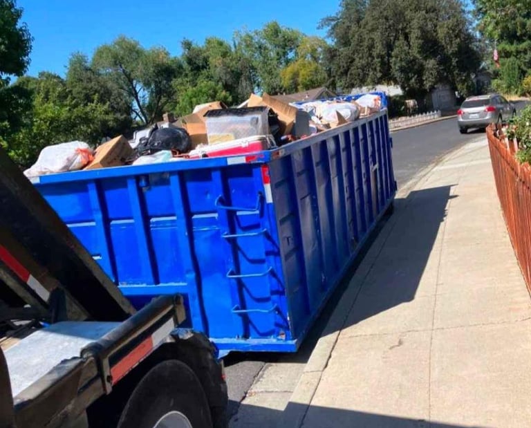 a dumpster truck with a large amount of trash in the back of it