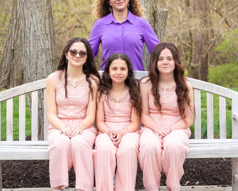 women in a purple shirt with three girls all wearing pink