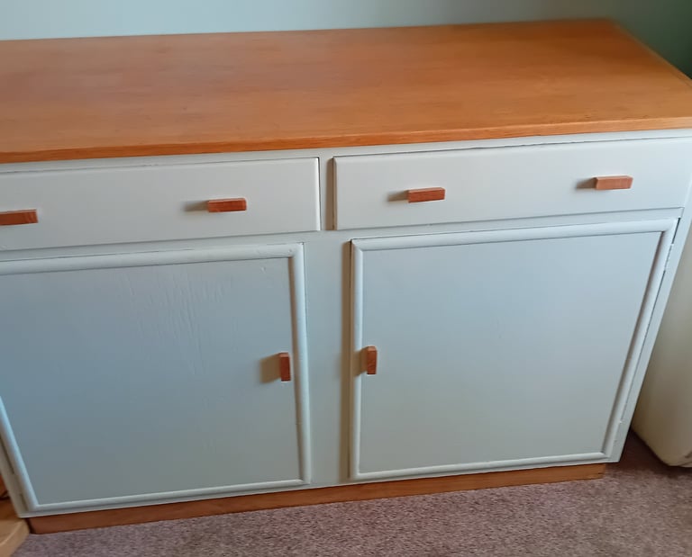 Finished cupboard painted a very light green with natural oak top and handles.