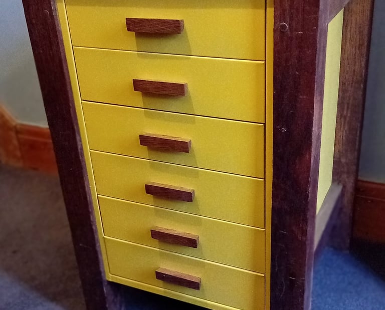 Bright yellow metal filing drawers with wooden handles with a wooden frame, legs and top