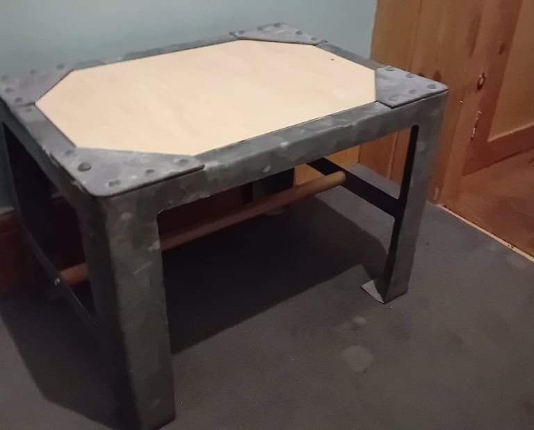 A plywood top has been added under the rivetted corners and wooden bar joining the 2 pairs of legs