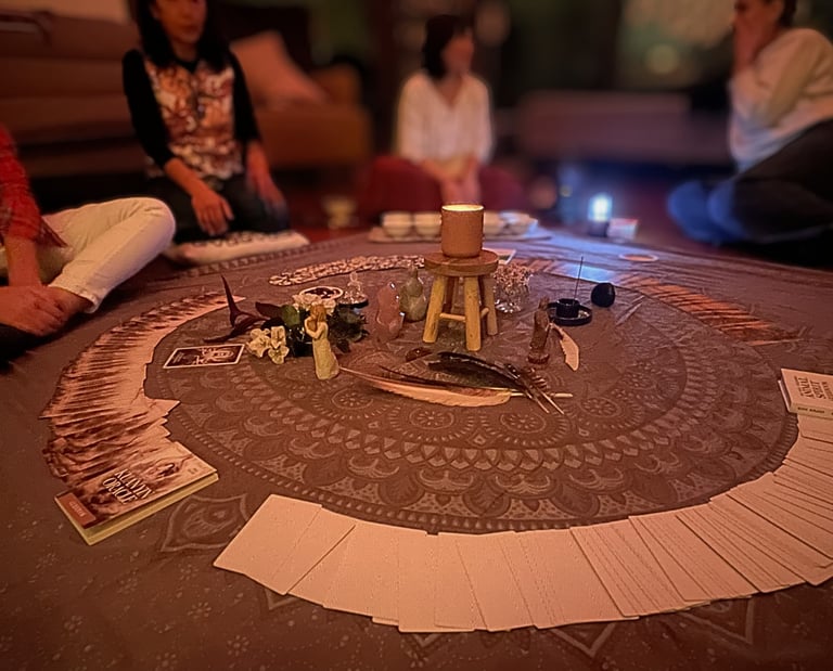 women sitting in circle around oracle cards and artefacts