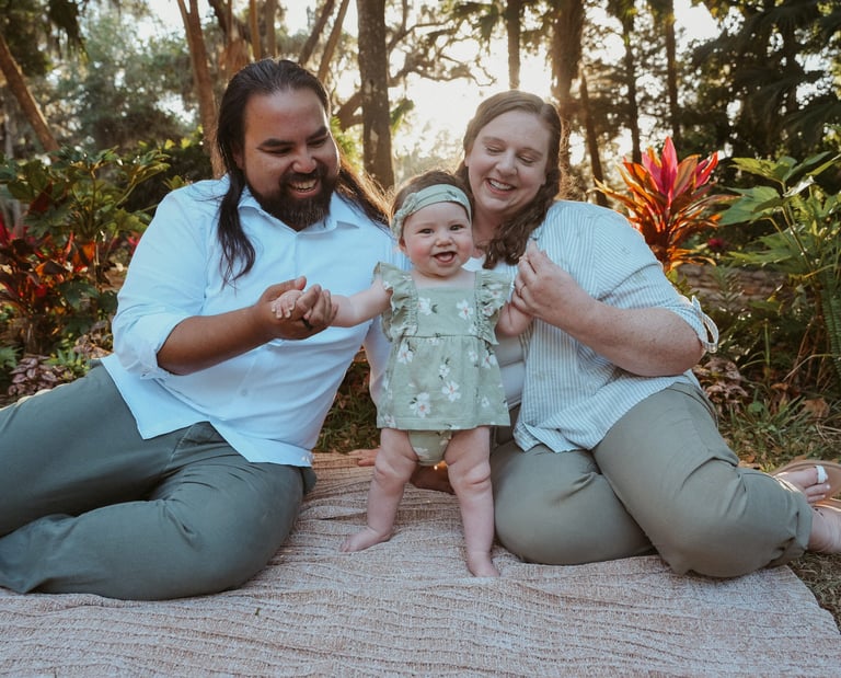 Family photo of Dr. Kevin Zelaya & Dr. Anna Abbott including their daughter with a sunset background