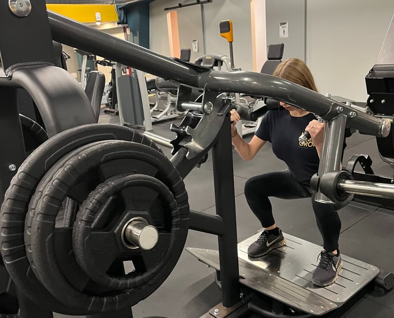 Donna che esegue squat su una macchina per leg press nella palestra Move 2 Grow a Milano, circondata da attrezzature per l'al