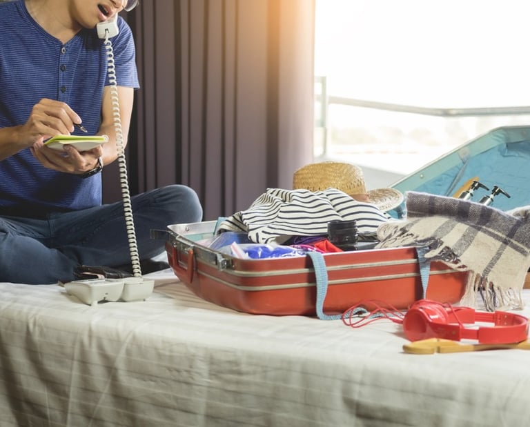 a man sitting on a bed with a suitcase and a phone