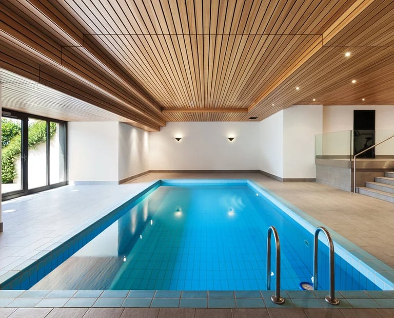 Modern luxury indoor swimming pool featuring a natural wood slat ceiling and bright blue tiling.