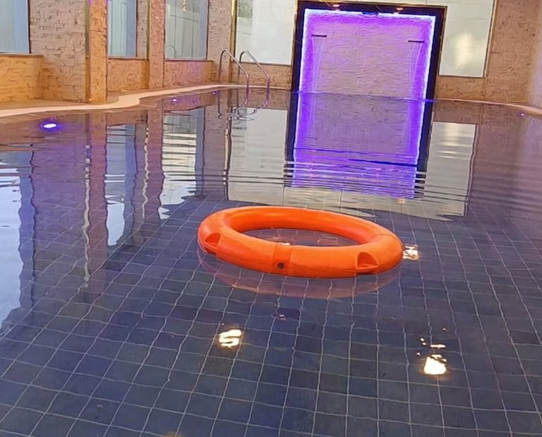Luxury indoor swimming pool with blue tiles, an orange lifebuoy, and purple LED lighting accents.
