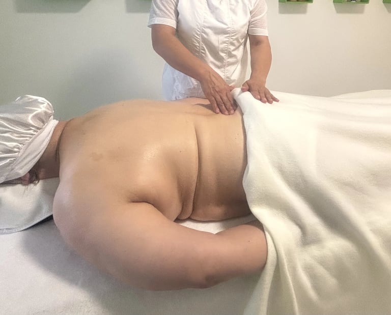 Wellness-Massage: Eine Masseurin massiert den Rücken einer liegenden Person.