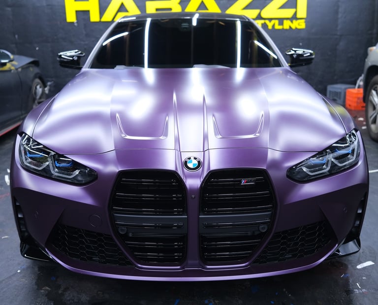 Front view of a BMW M4 with a matte metallic ppf car wrap at a professional auto styling shop.