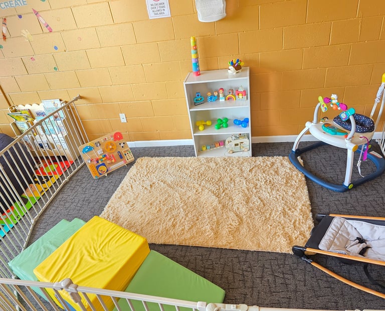 An infant play area with educational silicone and wooden toys, a soft rug, and foam climbing blocks.