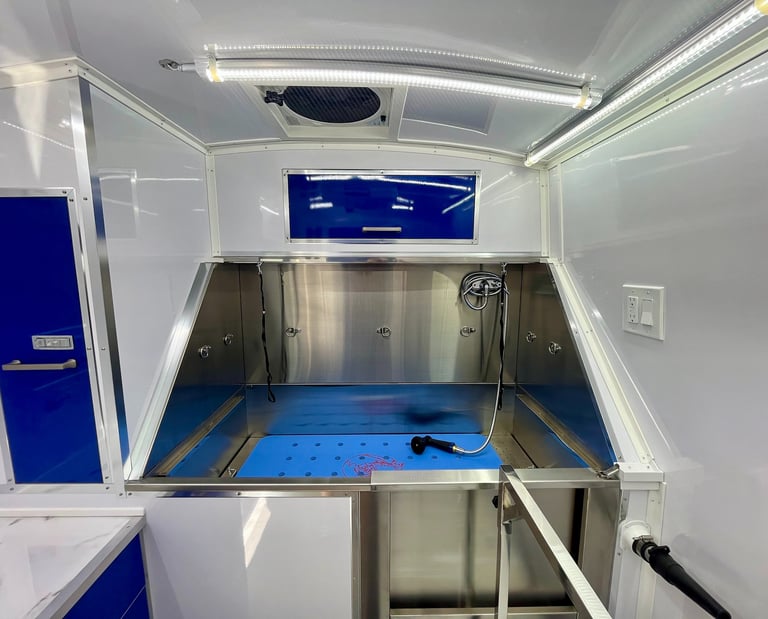 Professional stainless steel dog grooming bathtub inside a clean, fully equipped mobile grooming van