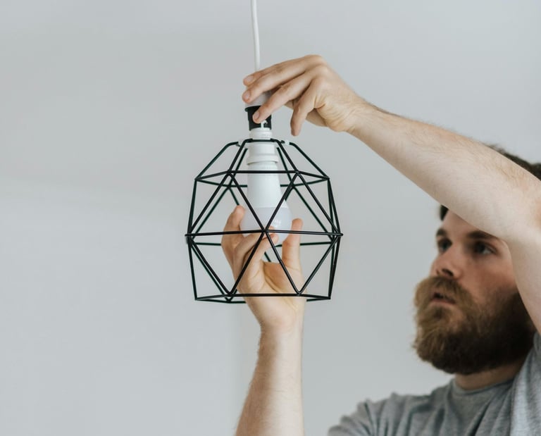 a man screwing a light bulb into a light fixture above him