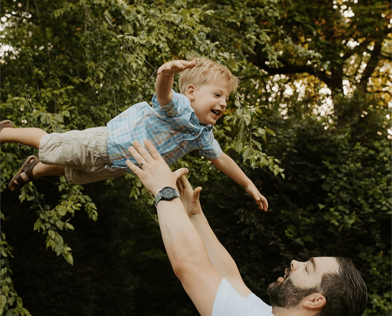 Brian Hess, owner, throwing son up in the air with trees in the background