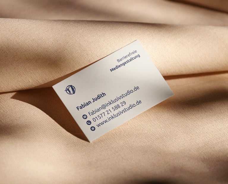 Visitenkarte von Fabian (inklusivstudio) mit Kontaktdaten liegt auf Leinentuch