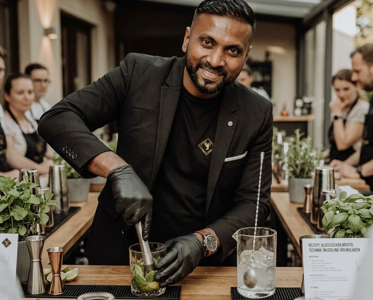 Professional mixologist muddling fresh mint for a mojito cocktail at a bartender training class.