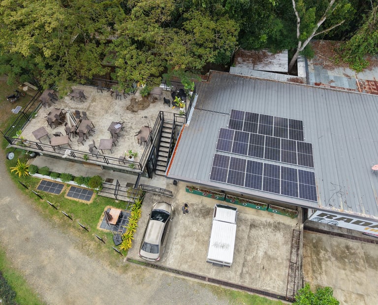 Aerial view of a restaurant with solar panels on the roof and an outdoor patio dining area.