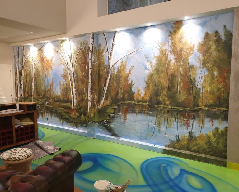 Quadro murale dipinto a mano con lago nel bosco e betulle su una parete interna.