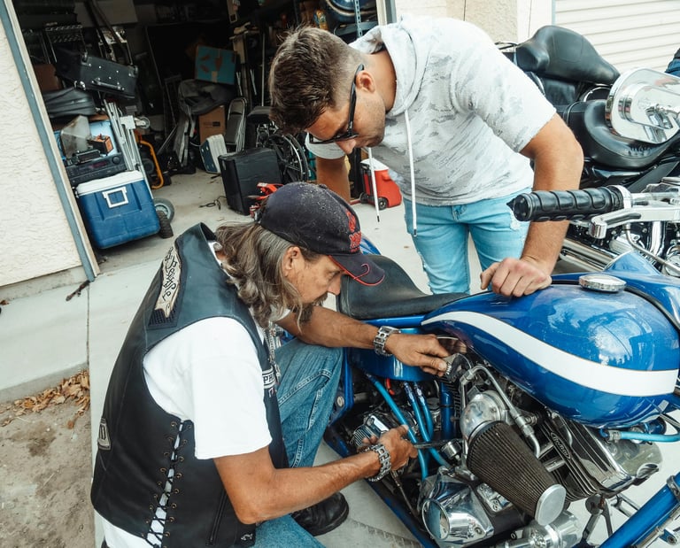 Father performing basic vehicle maintenance demonstration at The Forge workshop