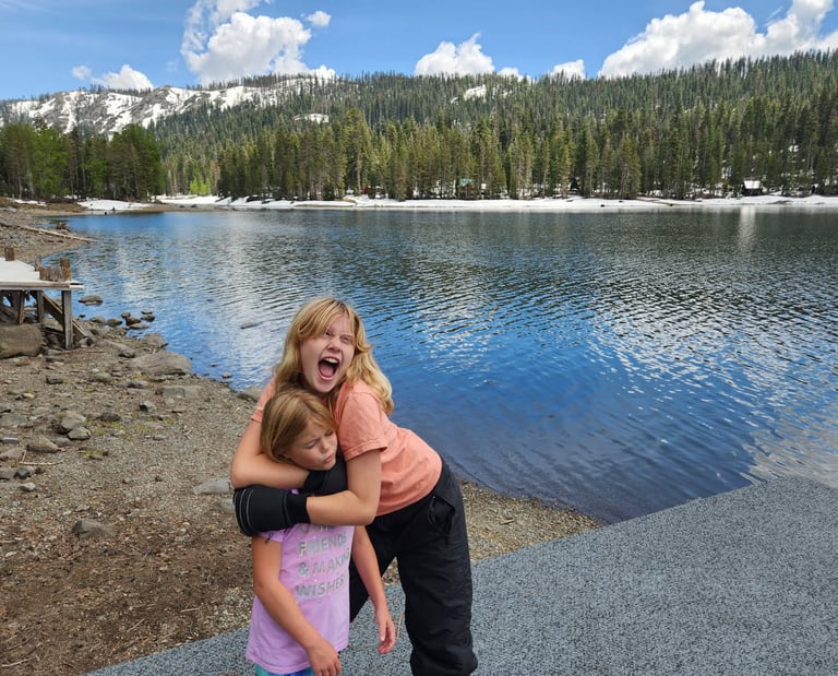 Cecelia and Mary Grace hugging by a lake