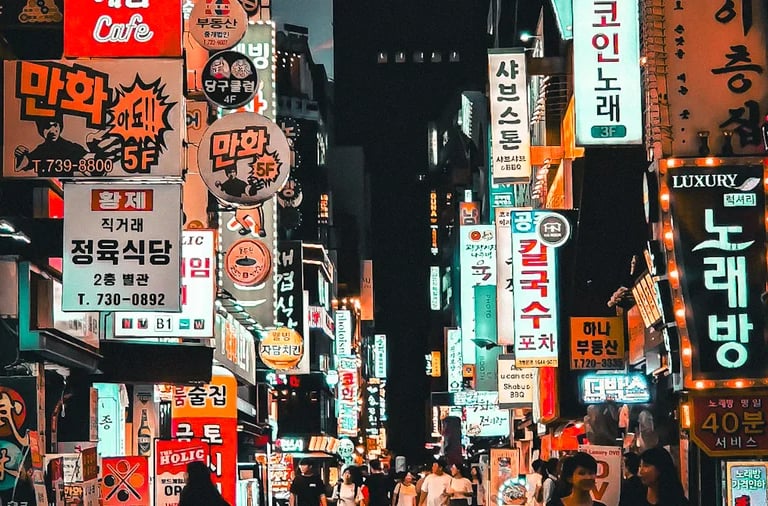 Vibrant night scene of a crowded Seoul street filled with glowing neon Korean business signs and pedestrians.