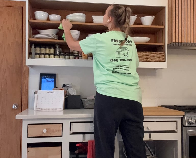 A professional cleaner thoroughly cleans a kitchen shelf with dishes