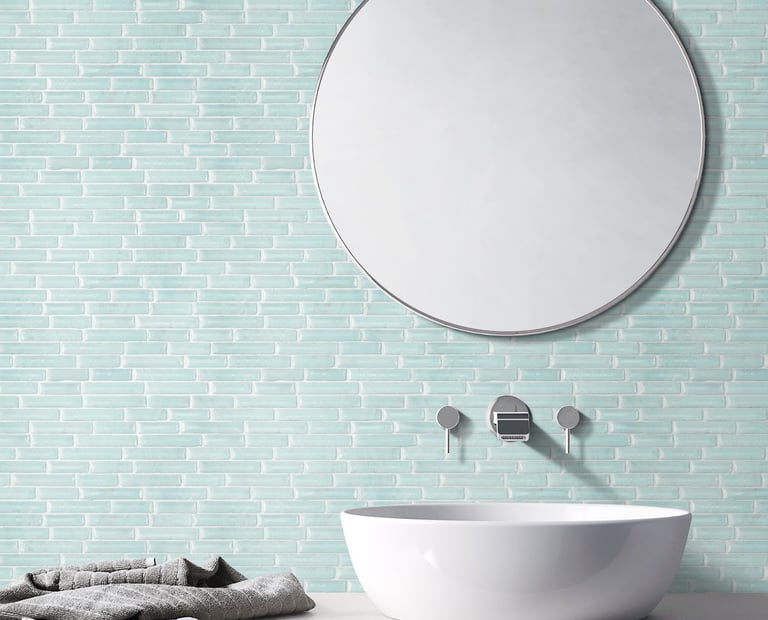 a bathroom sink with a mirror and a towel, green glass mosaic on the background wall
