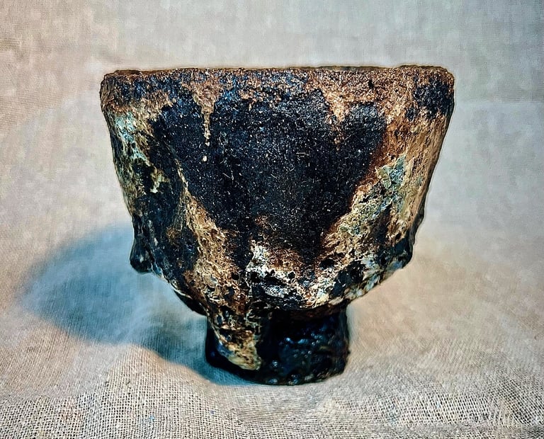 A handbuilt chawan cup for tea ceremony with  black, brown and green stone matt texture