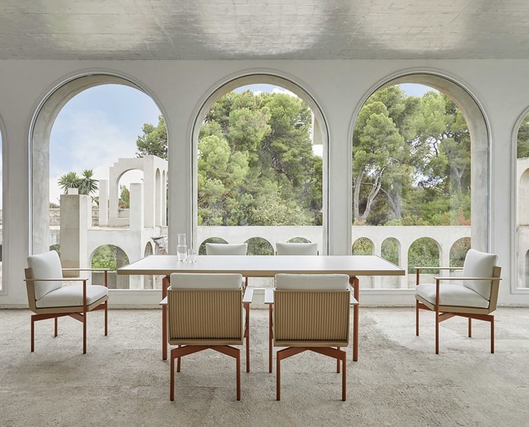 Conjunto de mesa de jantar e cadeiras de design em varanda com arcos brancos e jardim ao fundo — cur