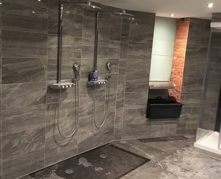 Badkamer met grijze tegels en zwart inloopdouche 