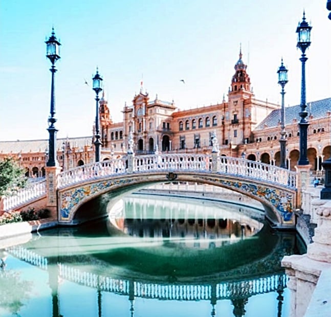 The ornate Plaza de Espana bridge and canal with historic architecture in Seville, Spain.