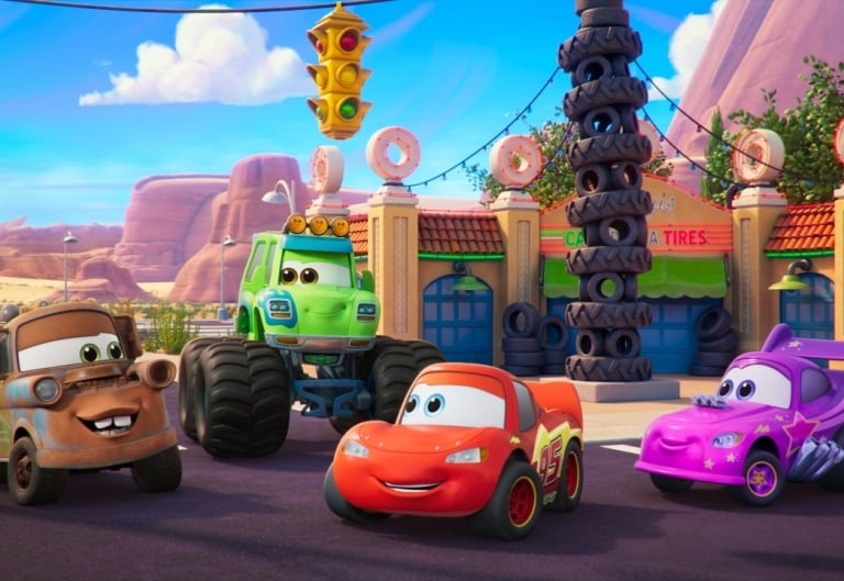 Disney Cars cast in front of Radiator Springs backdrop.