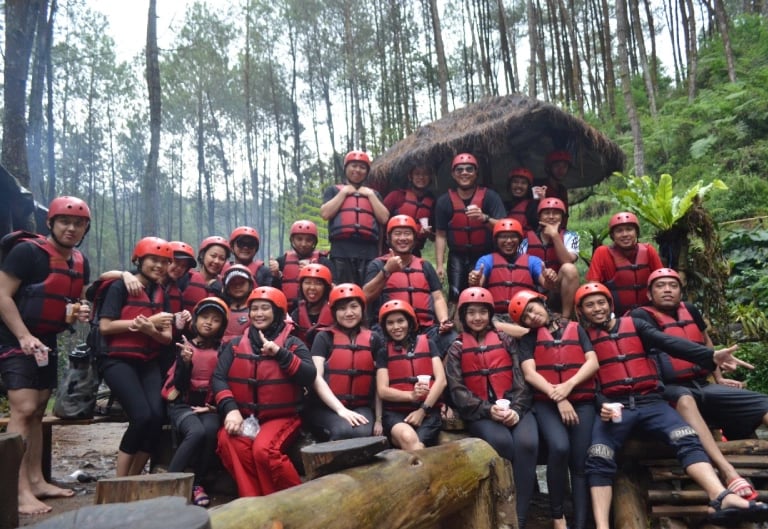 Foto karyawan perusahaan saat gathering atau team building outdoor, mengenakan alat keselamatan arung jeram di tengah hutan p
