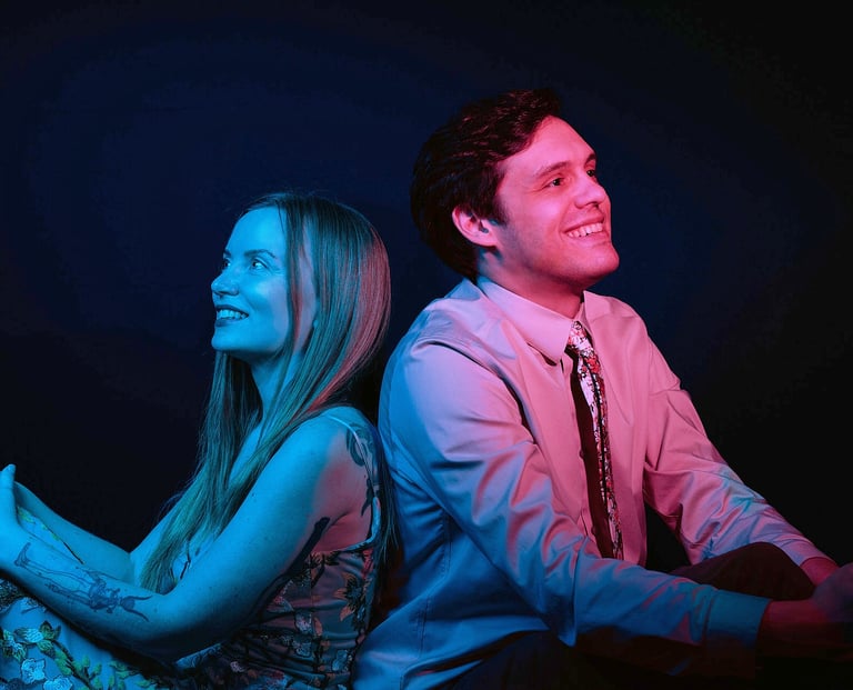 a man in red light and woman in blue light sitting back to back looking at opposite direction