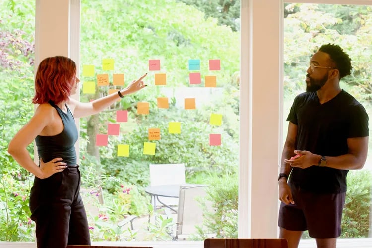 deux personnes réflechissent à leur team building à Montpellier en mettant des post-it à la fenêtre