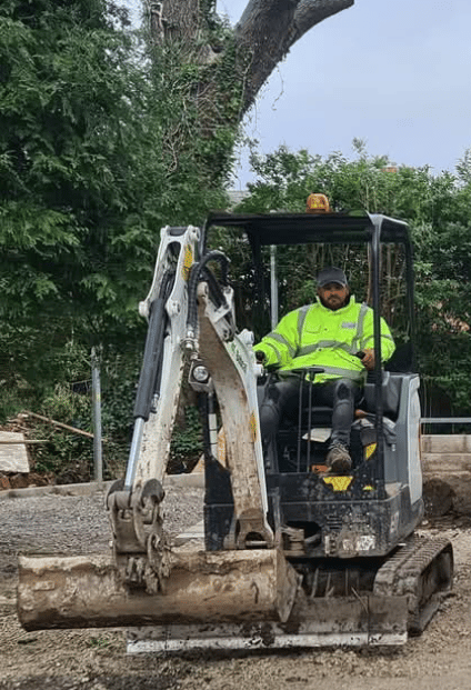 Mini digger with driver at work in Winchmore hill London