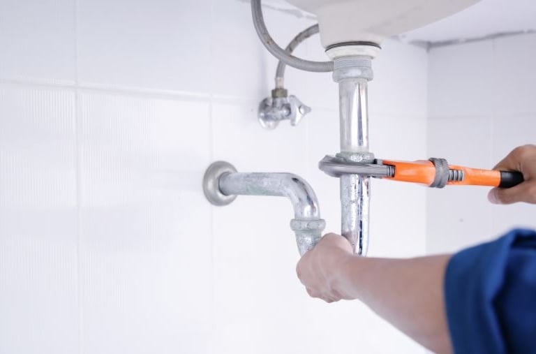 a plumber in a blue shirt is holding a wrenCH.