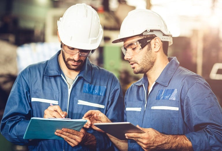 two men in blue workwears standing in a factory