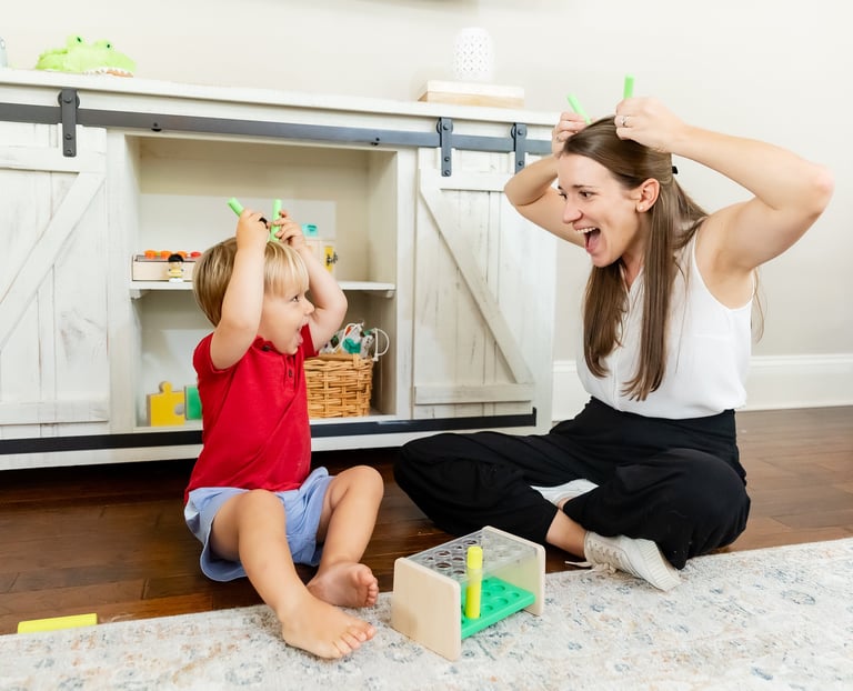 A therapist and child playing together, imitating each other making horns with a set of blocks 