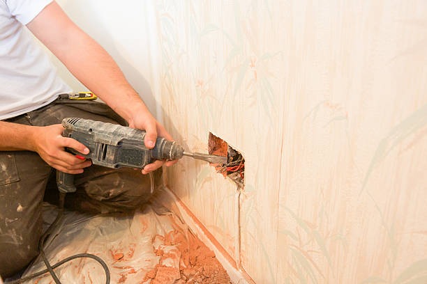 a man is using a drill in a wall to show rewire process