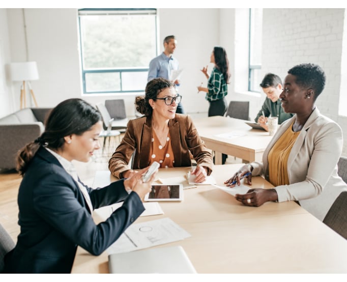 3 women talking over workdesk