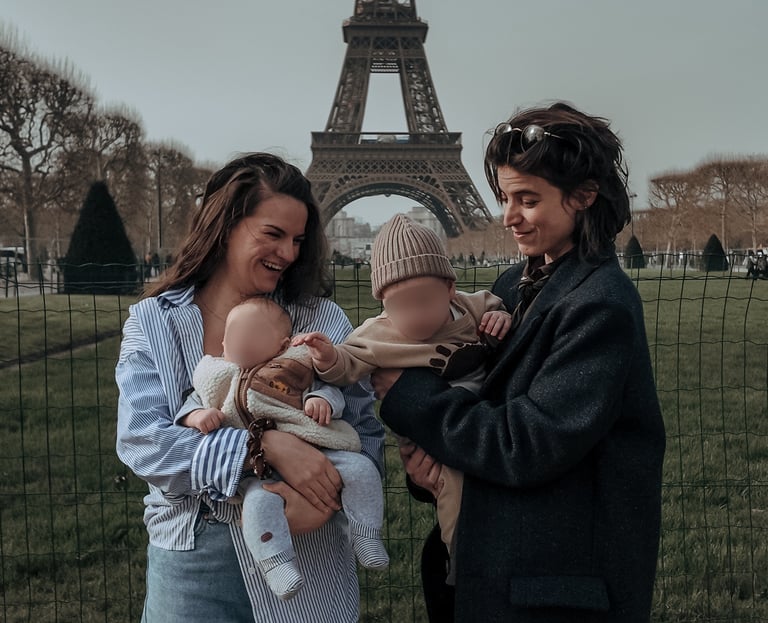Deux femmes heureuses tenant des bébés pendant des vacances en famille devant la Tour Eiffel à Paris