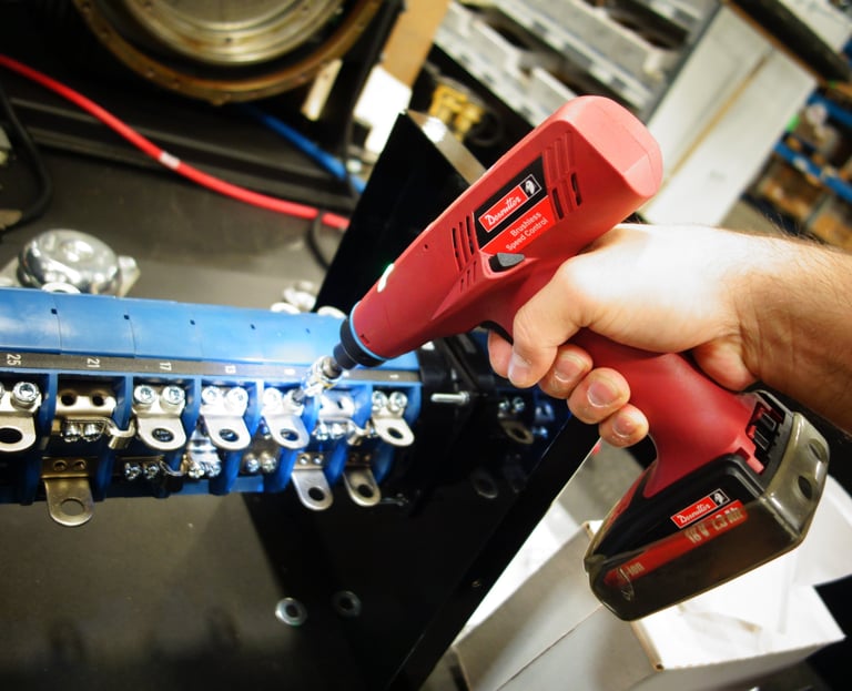 A technician uses a Desoutter cordless electric nutrunner to assemble an industrial electrical component.