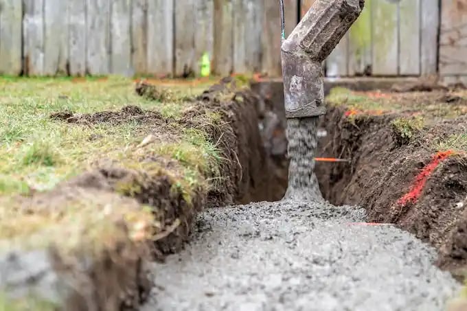 a concrete slab being poured into a trench