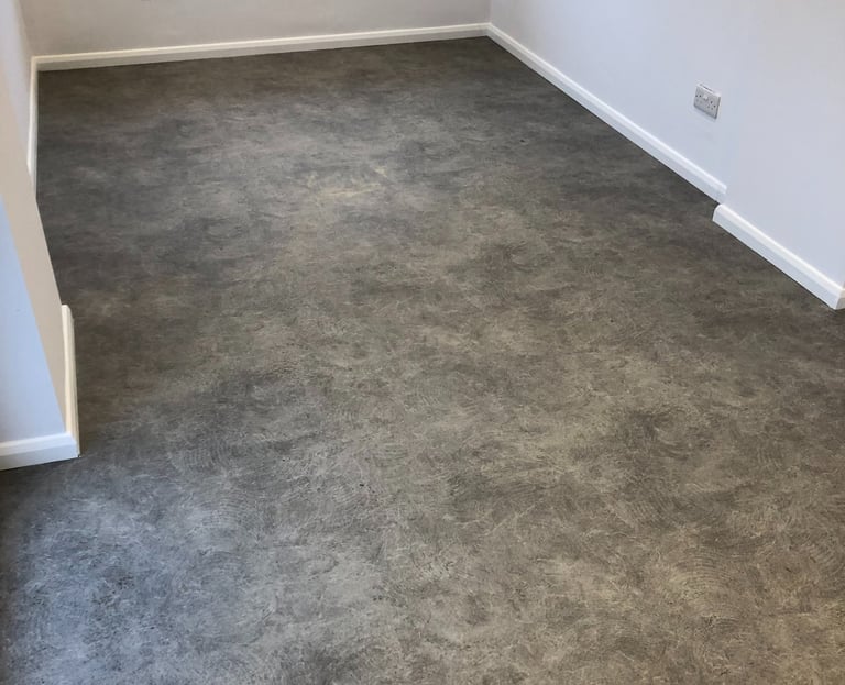 Portslade room featuring dark grey concrete effect luxury vinyl tile flooring and white walls.