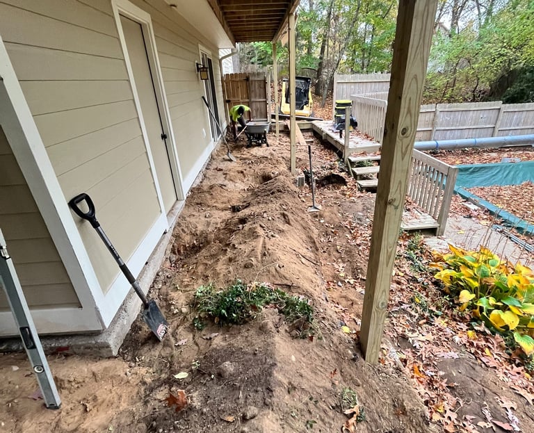 Landscaping contractor excavating dirt and grading soil for a backyard Patio project near a pool.