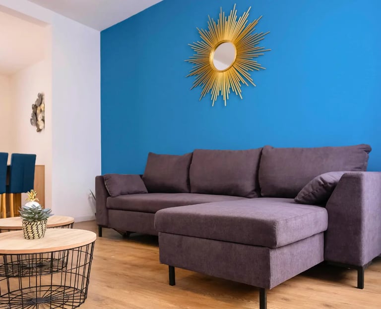 Salon lumineux avec canapé d’angle bleu, hébergement professionnel tout équipé