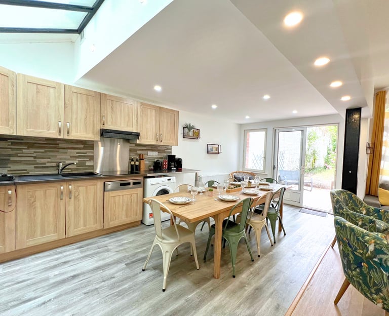 Grande cuisine équipée avec table pour groupe et accès direct au jardin privatif.