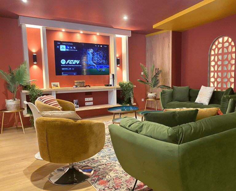 Salon de maison meublée avec canapés confortables et TV murale pour professionnels en séjour.