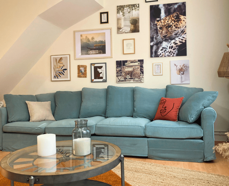 Salon décoré avec canapé bleu et murs ornés de cadres dans logement meublé.